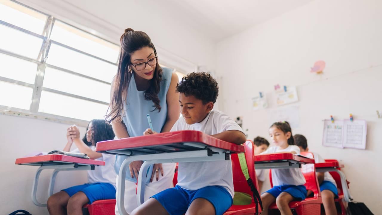 Professora auxiliando um aluno em sala de aula