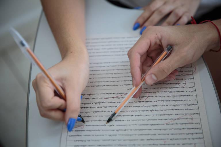 Estudantes escrevendo em um papel com canetas