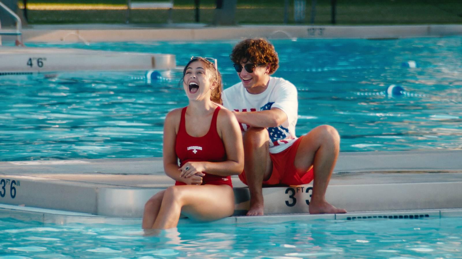 Gabriel LaBelle passando protetor solar nas costas de um salva-vidas em Snack Shack.
