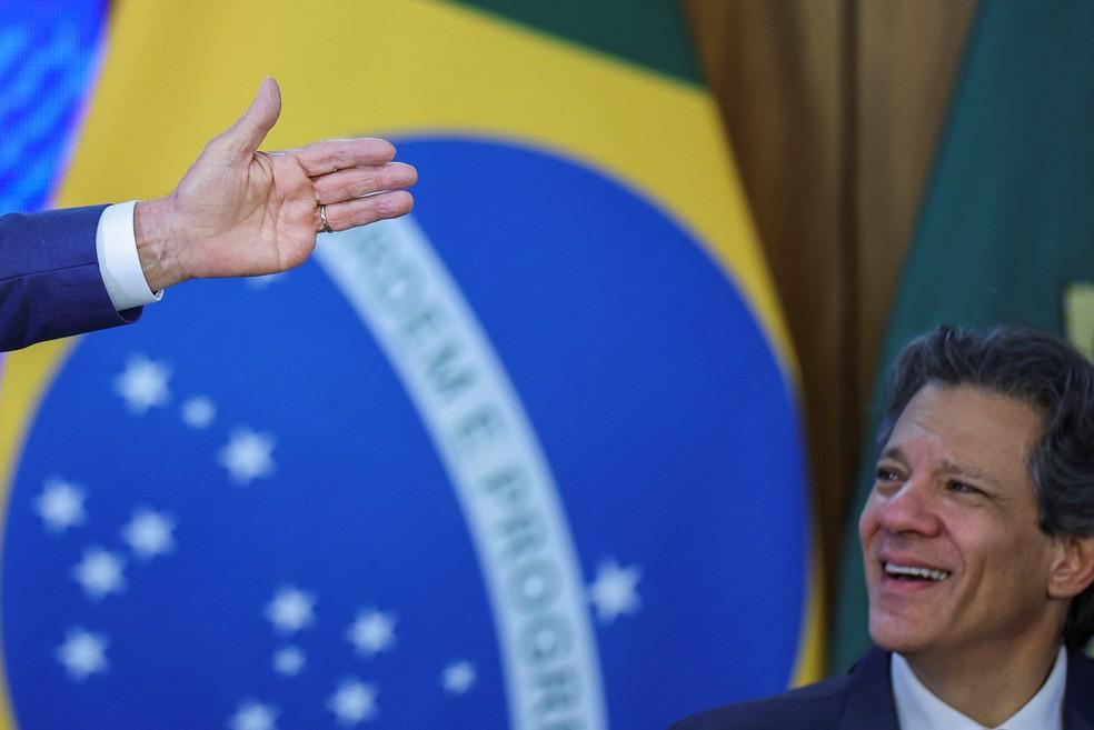 Haddad observa Lula falando durante evento sobre tarifaço