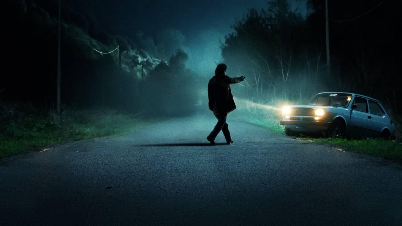 Foto promocional da série 'O Monstro de Florença', com um homem de costas em meio a um cenário escuro.