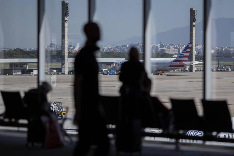 Área internacional do aeroporto do Galeão, Rio de Janeiro com pessoas e aeronave ao fundo.