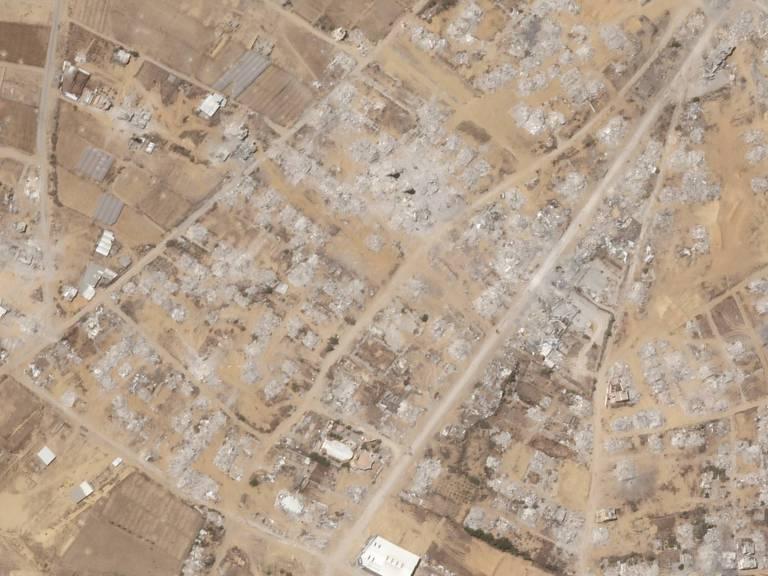 Vista aérea mostra área urbana com grande destruição, prédios em ruínas e escombros espalhados.