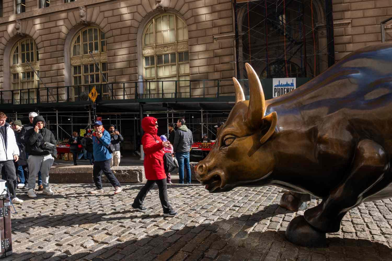 Pedestres perto da estátua do touro de Wall Street em Nova York, novembro de 2025.