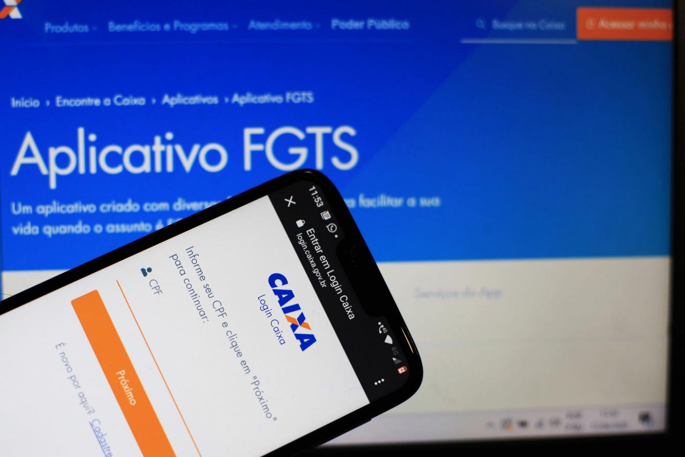 Celular e tela de computador abertos na aba do FGTS do site da Caixa