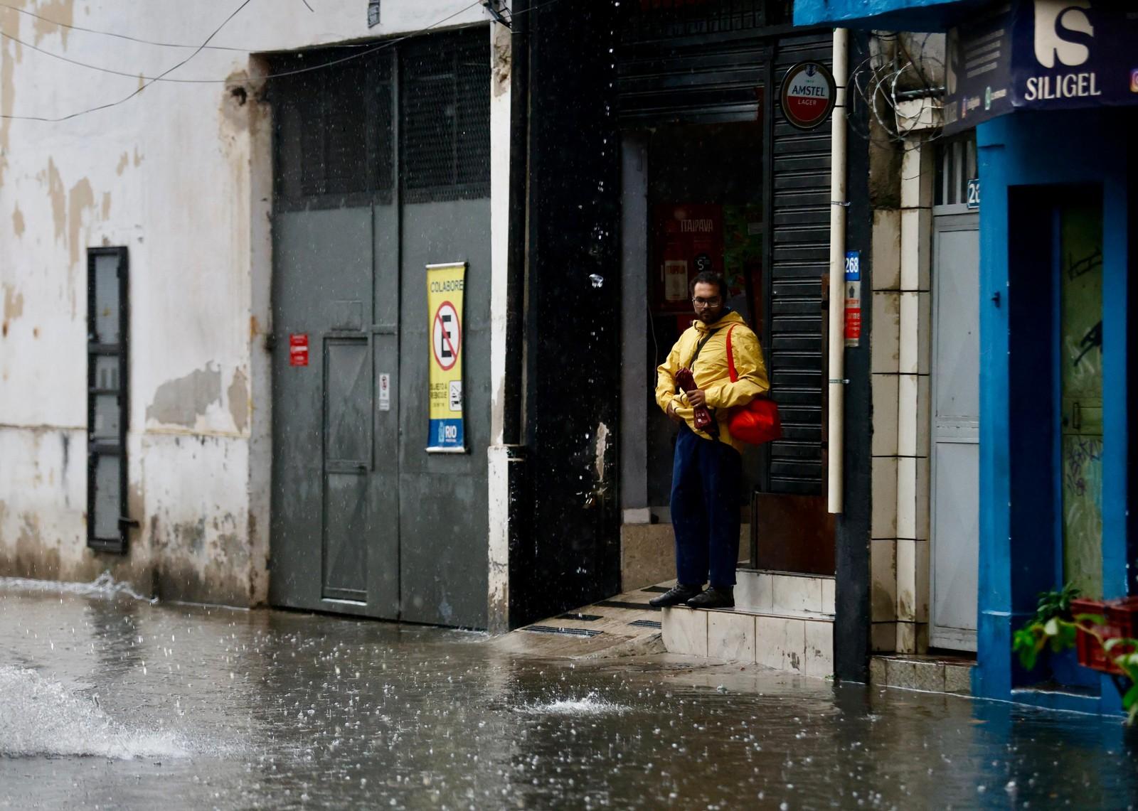 Pedestre se protege da chuva na Rua General Bruce
