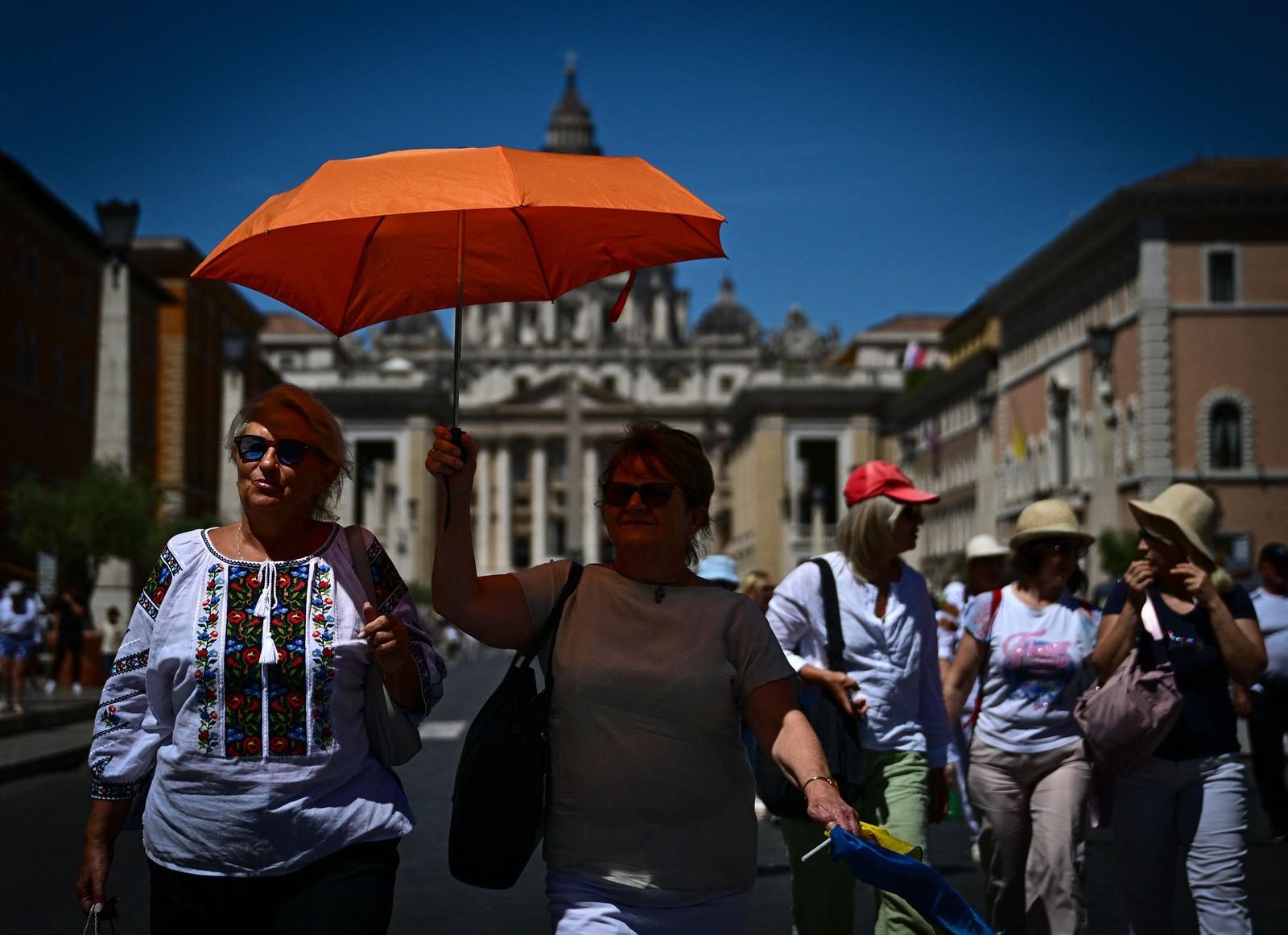 Mulher segura um guarda-chuva para se proteger do sol em um dia quente de verão, em Roma.