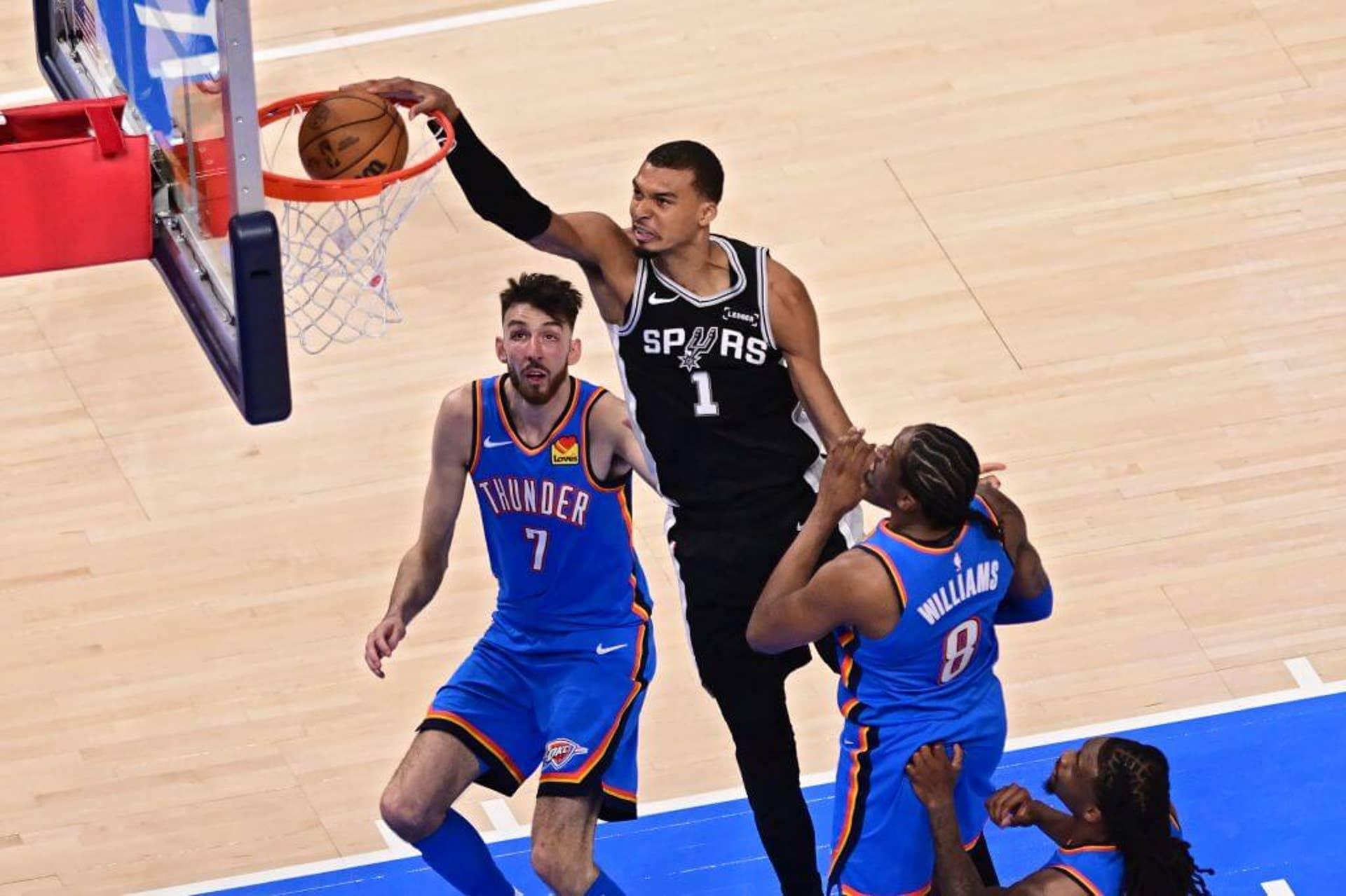 Victor Wembanyama em uma enterrada com jogadores do Thunder ao fundo.