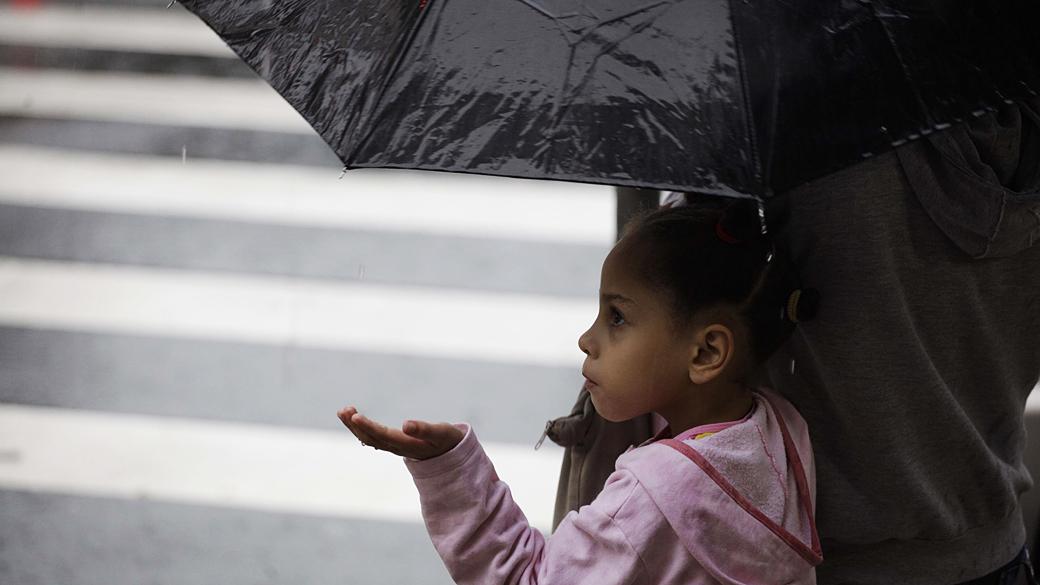 Pessoas se protegem da chuva e do frio que atinge a cidade de São Paulo, durante a manhã no centro da capital.