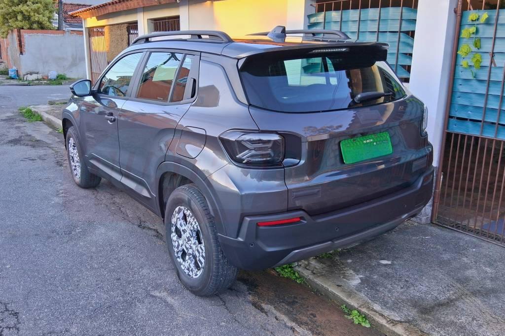 SUV cinza escuro com teto solar e rack de teto.