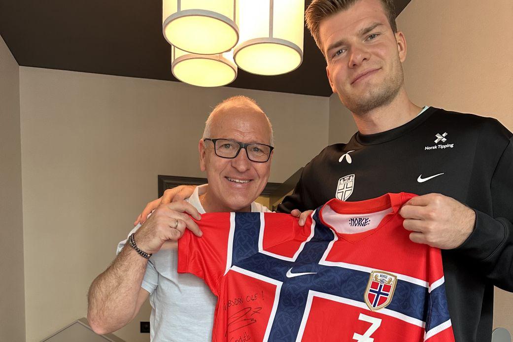 Gøran Sørloth e seu filho Alexander segurando uma camisa da Noruega juntos.