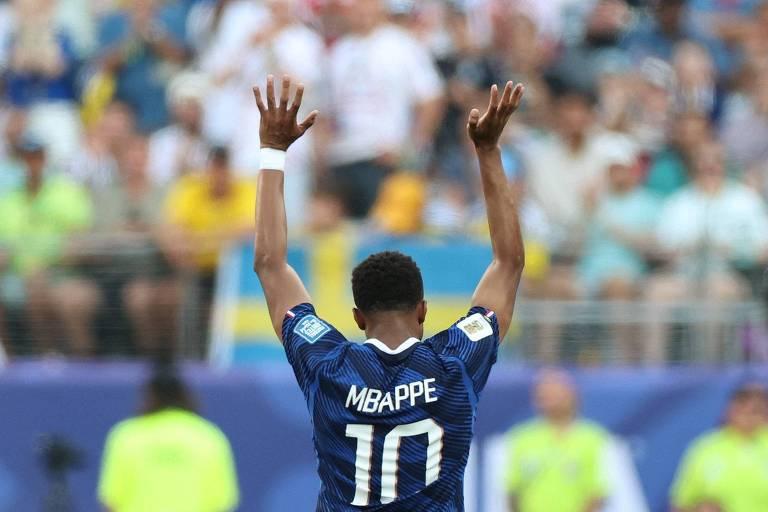 Jogador Mbappé, camisa 10 da França, de costas levantando os braços