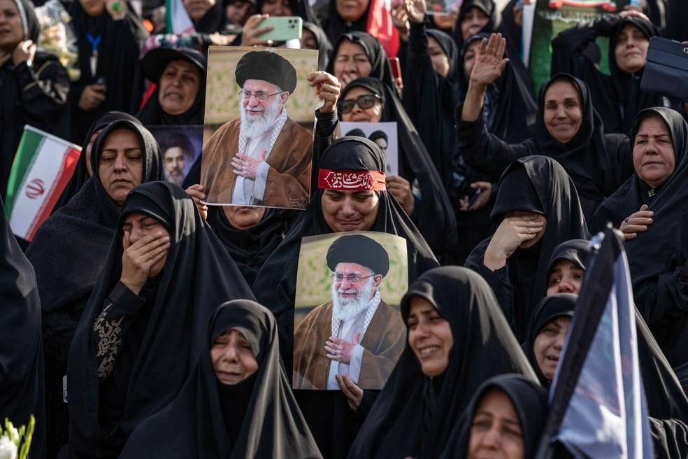 Enlutados seguram retratos de Ali Khamenei durante o funeral.