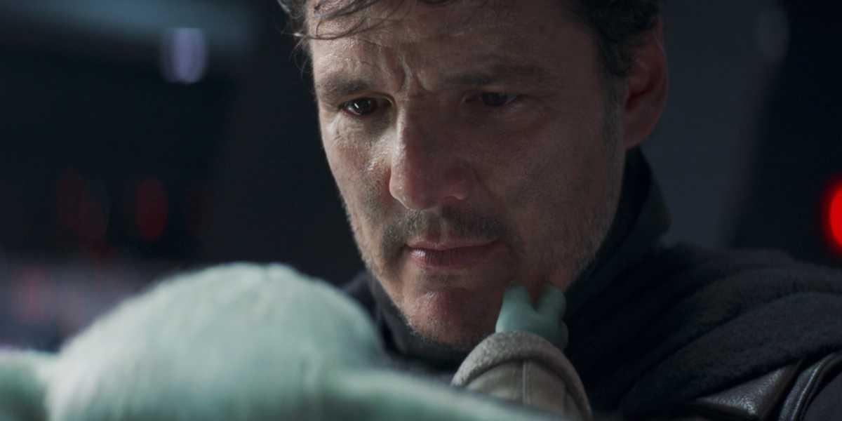 Din Djarin (Pedro Pascal) holding Grogu in 'The Mandalorian'.