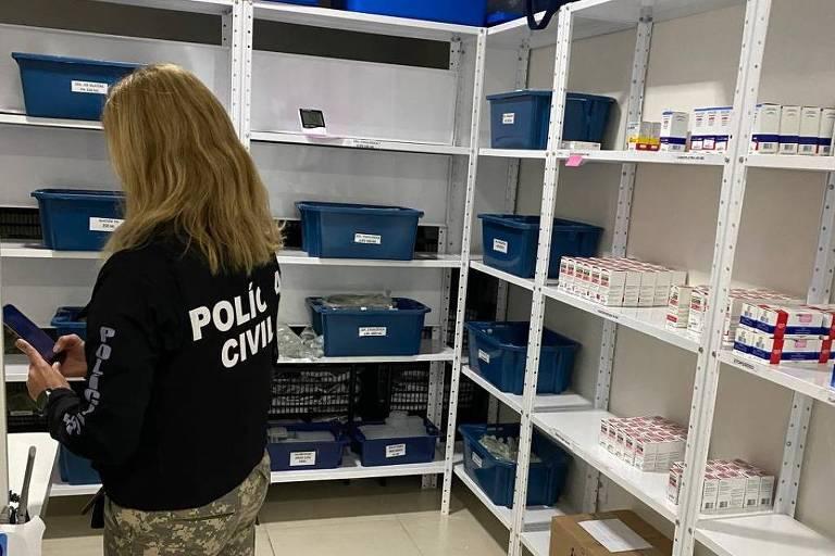 Agente da Polícia Civil em sala com prateleiras de medicamentos