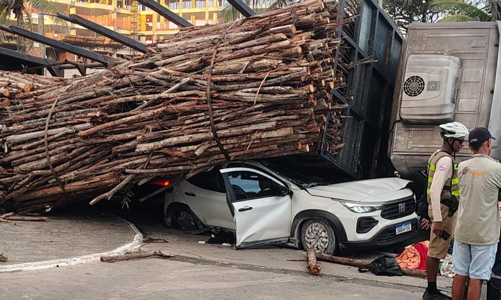 Carga de madeira cai de caminhão, esmaga carro e deixa uma pessoa ferida em Salvador