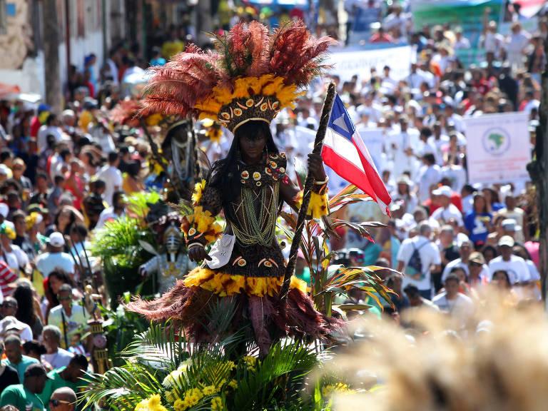 Imagem da cabocla, adorada com penas na cabeça e com a bandeira da Bahia nas mãos