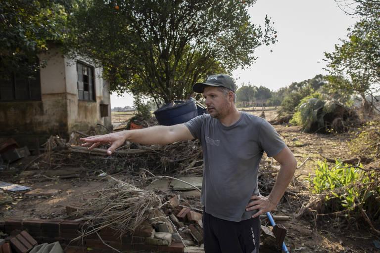 Agricultor mostra os estragos da enchente em sua propriedade rural em Cruzeiro do Sul (RS) em 2024. Ele usa camisa cinza e boné.