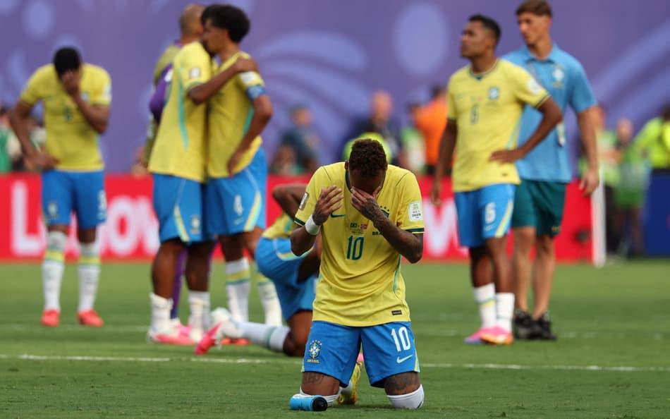 Neymar cabisbaixo e ajoelhado em campo.